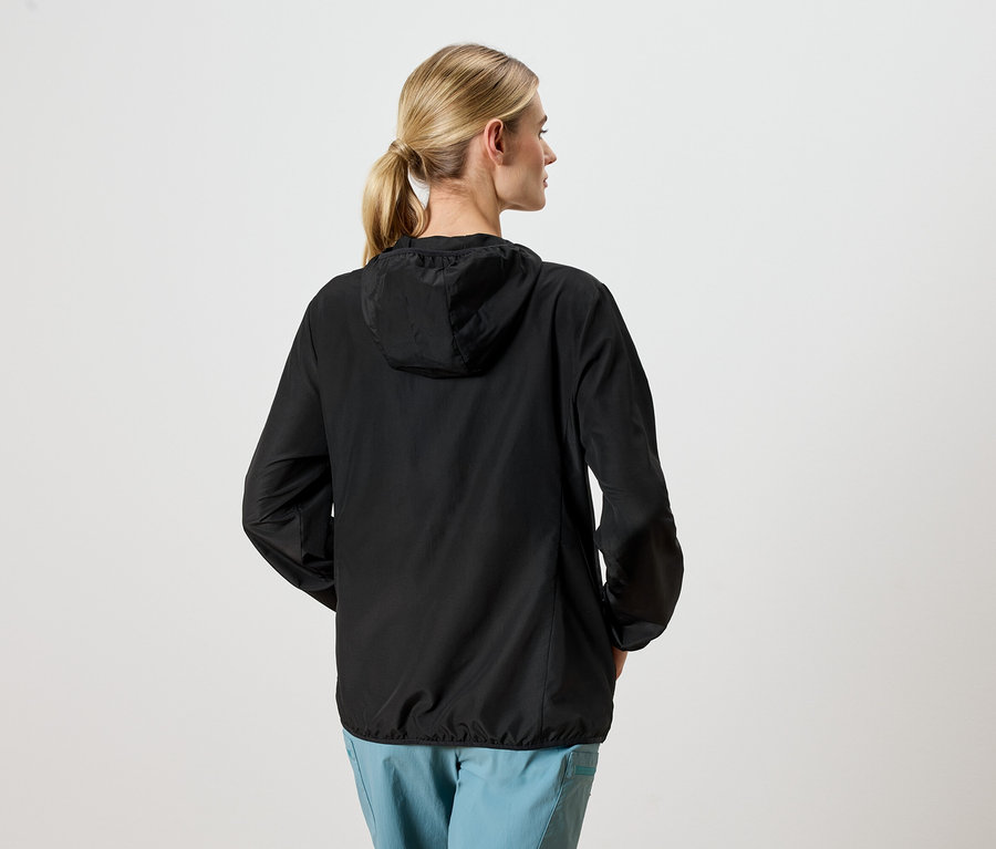 Frau von hinten in einer schwarzen Jacke und blauen Hosen.