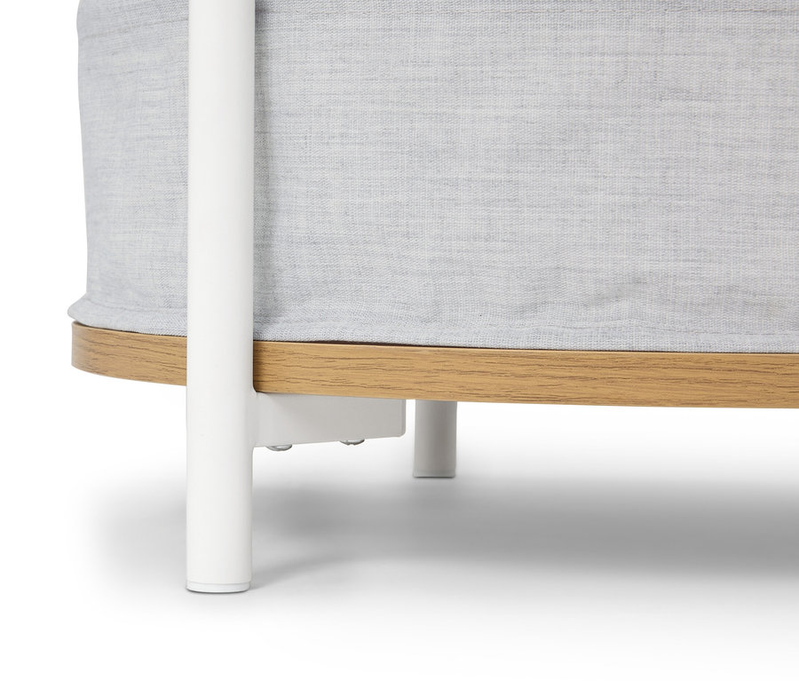 Detailansicht eines runden Babybettes mit hellgrauem Stoff und hellbraunem Holzfuß, der auf einem weißen Untergestell steht.