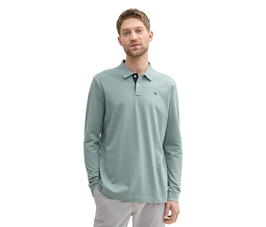 Mann mit Tom Tailor Longsleeve Piqué Poloshirt, Grey Mint und grauer Hose steht vor weißem Hintergrund.