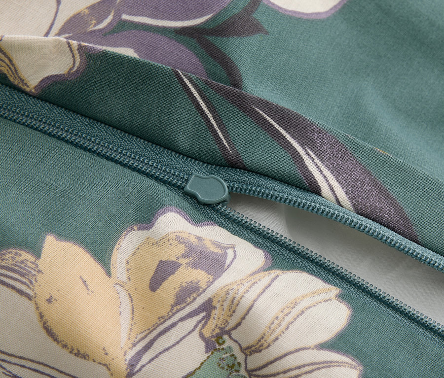 Detailaufnahme eines Reißverschlusses auf einem grünlichen Stoff mit Blumenmuster.