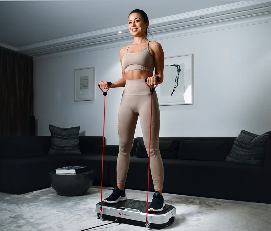 Frau trainiert mit Christopeit Vibrationstrainer Vibro VBT 4200 und roten Widerstandsbändern.