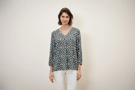 Frau trägt eine Bluse in Crinkle-Optik und weiße Hose.