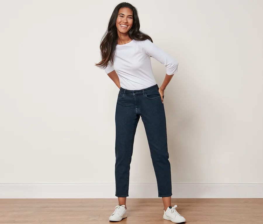 Frau posiert in High-Waist-Jeans und weißem T-Shirt.