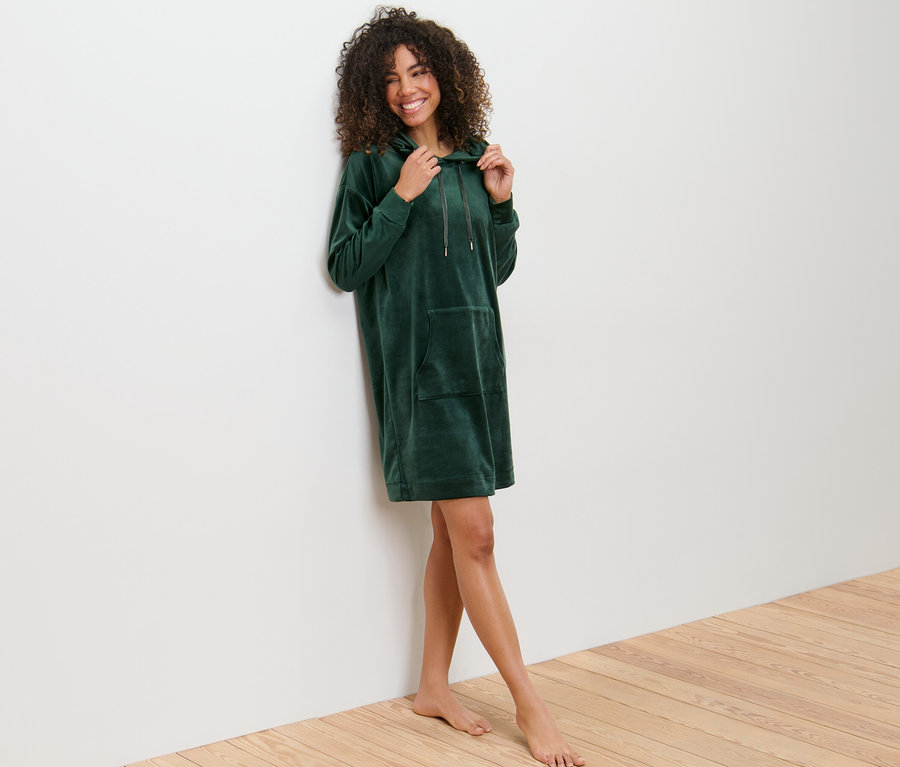 Frau lächelt und posiert in einem Nicki-Loungewear-Kleid.