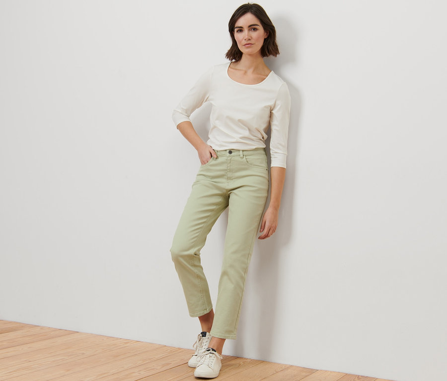 Eine Frau posiert in grünen Modern Colored Jeans – Fit »Ava« und einem weißen Oberteil.