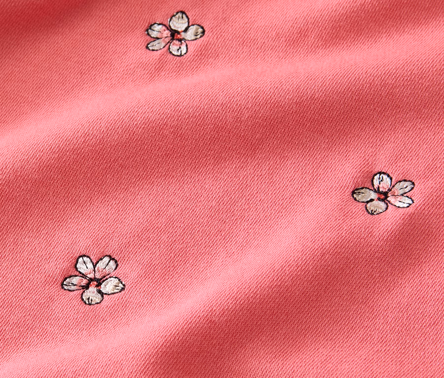 Detailaufnahme eines rosafarbenen, bestickten Sweatshirts.