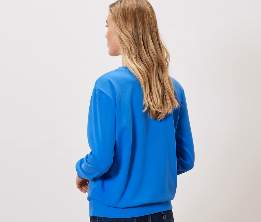 Frau von hinten trägt kobaltblaues Sweatshirt.