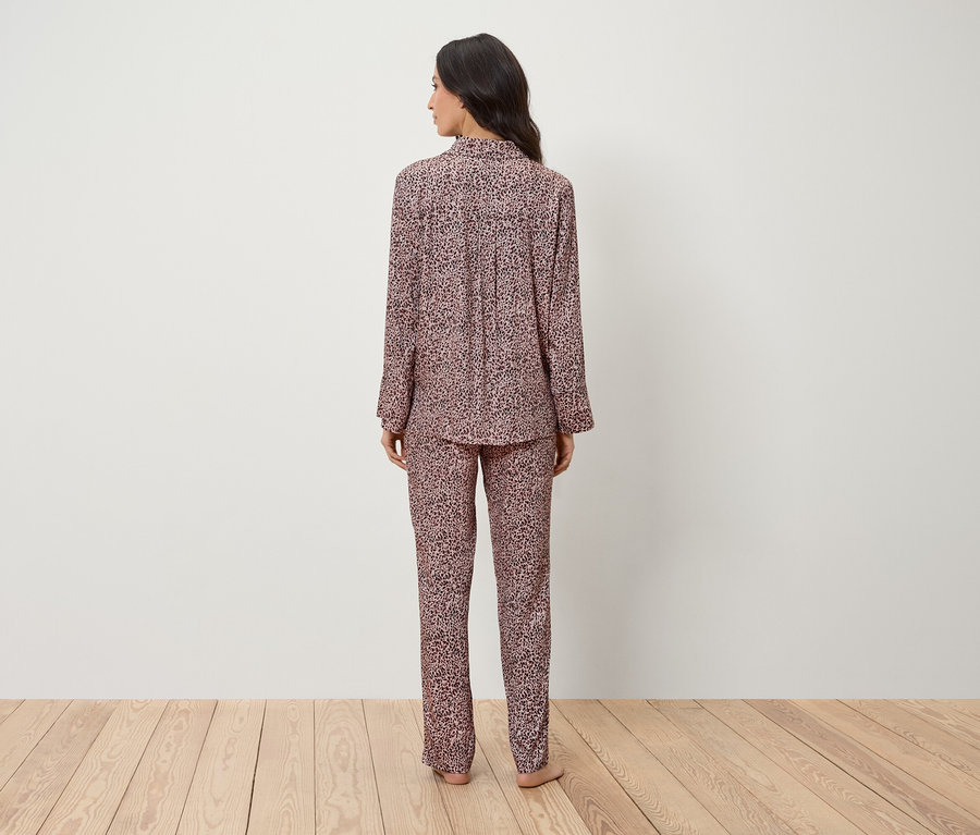 Frau steht mit dem Rücken zur Kamera und trägt einen rosa Pyjama mit Tiermuster.