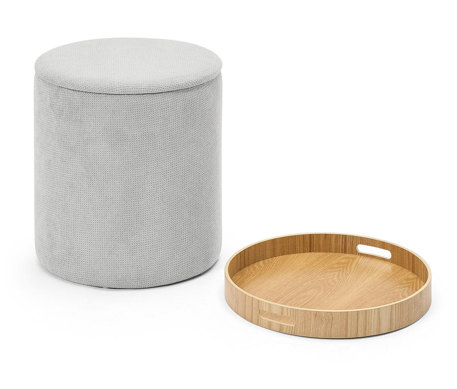 Ein grauer Stoffhocker neben einem runden Holztablett.