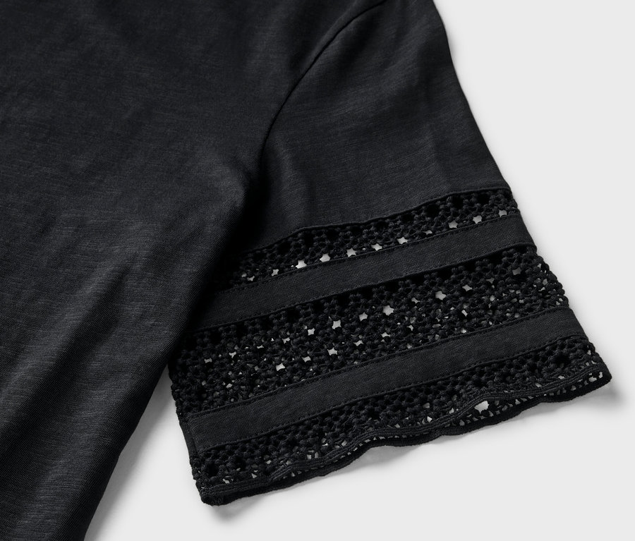 Detailaufnahme eines schwarzen Shirts mit Stickerei am Ärmel.