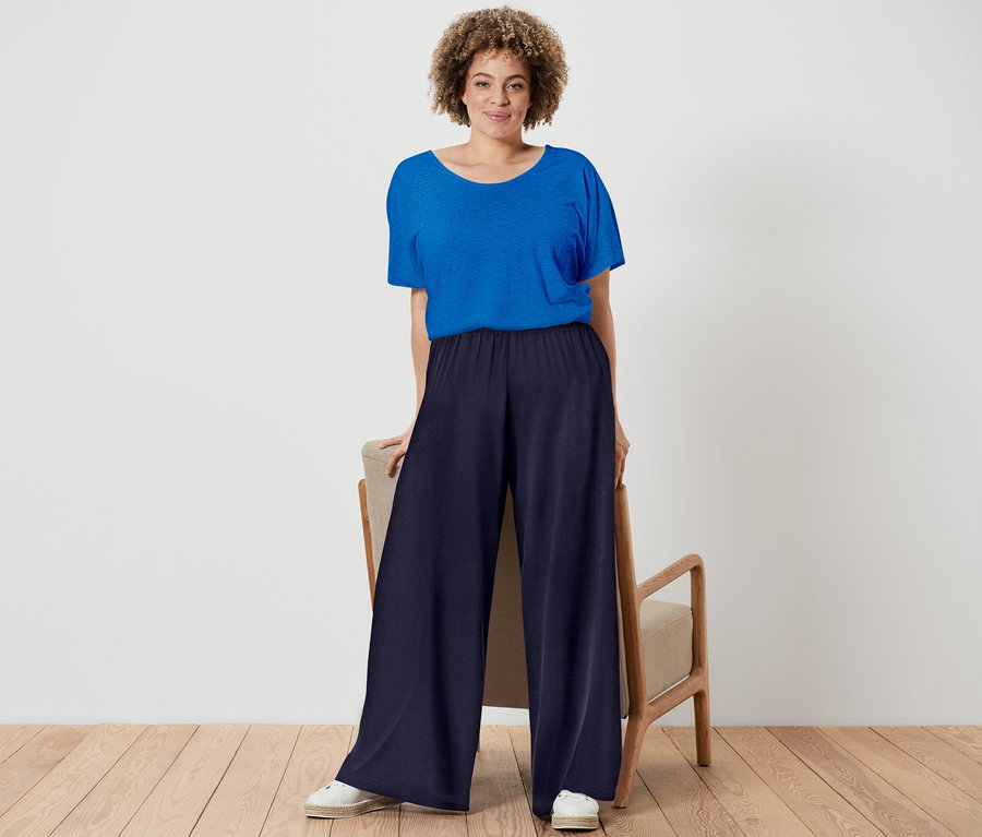 Frau posiert in kobaltblauem Shirt aus Leinenmix und dunkelblauer Palazzohose.