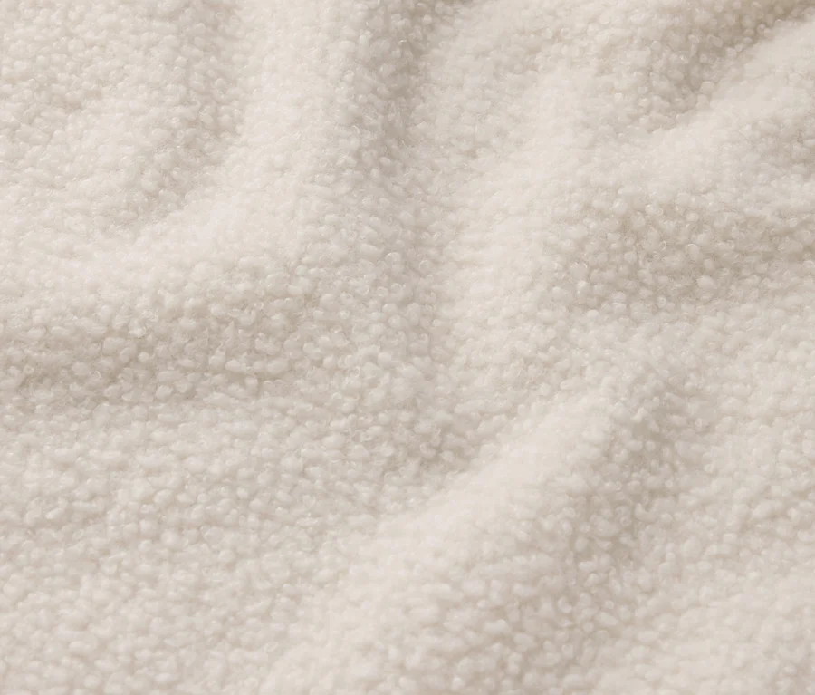 Detailaufnahme eines cremefarbenen Shearling-Stoffs.