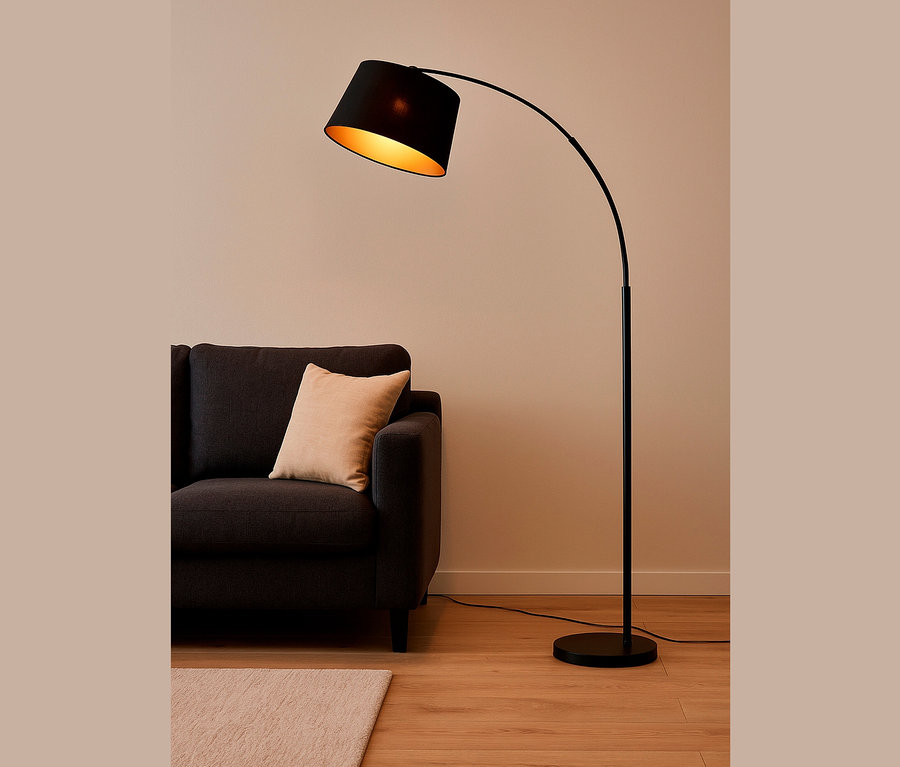 Eine schwarze Bogenlampe steht neben einem grauen Sofa mit einem beige Kissen.