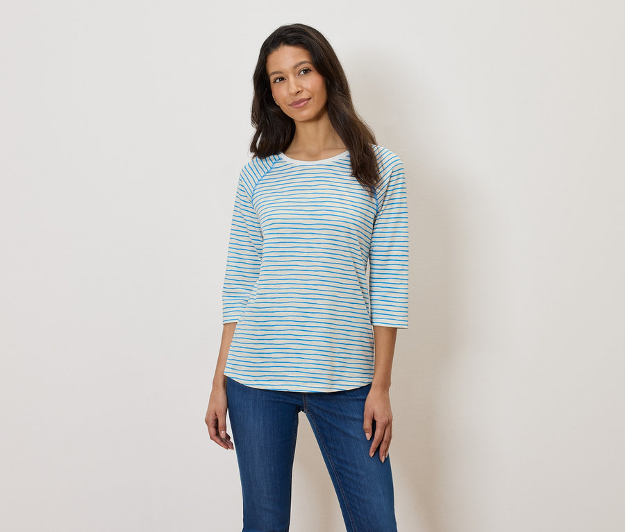 Frau trägt ein blau-weiß gestreiftes Langarmshirt und blaue Jeans.