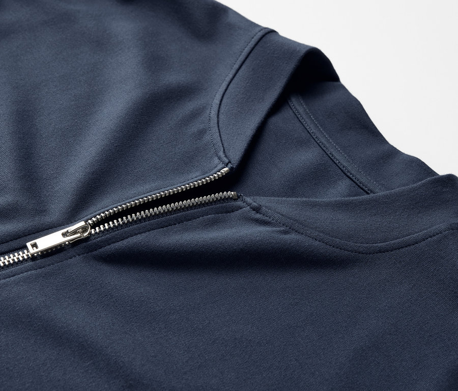 Detailansicht einer marineblauen Sweatjacke mit silbernem Reißverschluss.