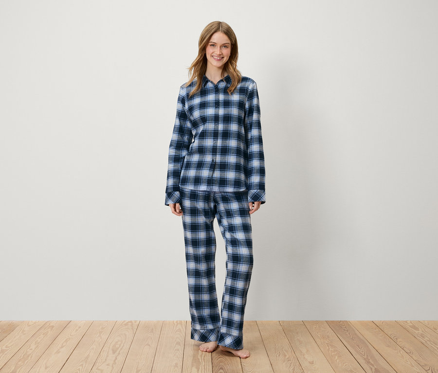 Eine Frau steht und trägt einen blau karierten Pyjama.