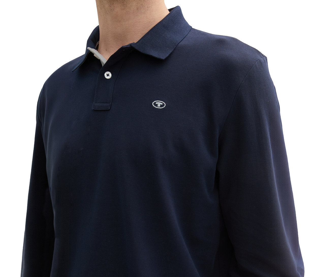 Nahaufnahme einer Person, die ein Tom Tailor Longsleeve Piqué Poloshirt in Sky Captain Blue trägt.