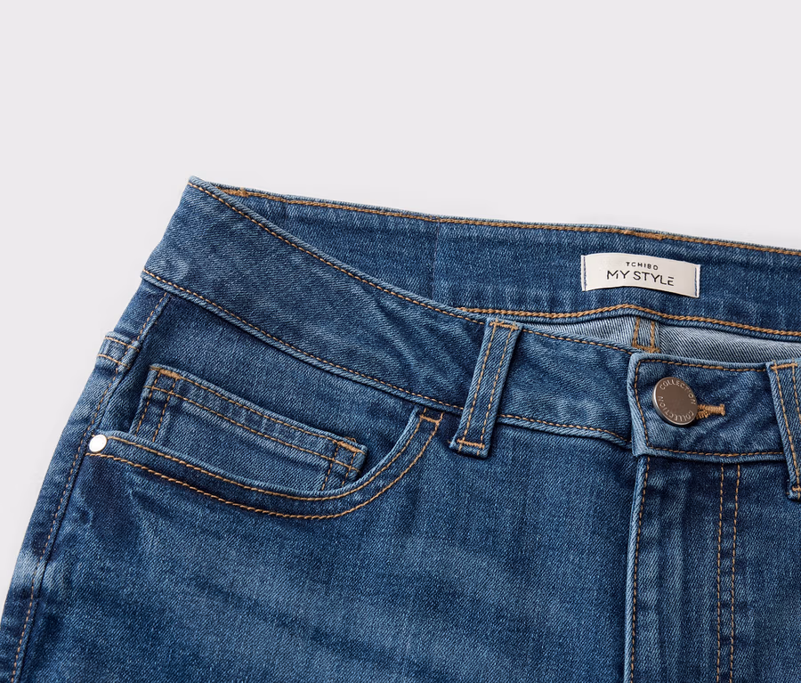 Nahaufnahme von Jeansstoff mit Taschen und einem 'TCHIBO MY STYLE'-Etikett.