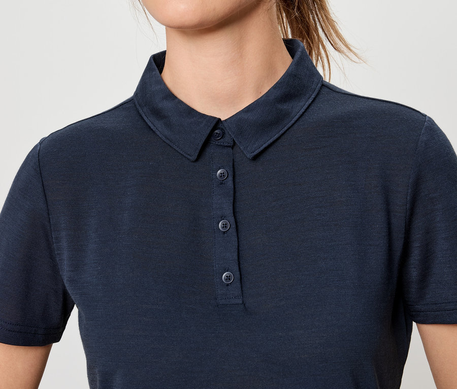 Nahaufnahme einer Frau, die ein dunkelblaues Poloshirt mit Knöpfen trägt.