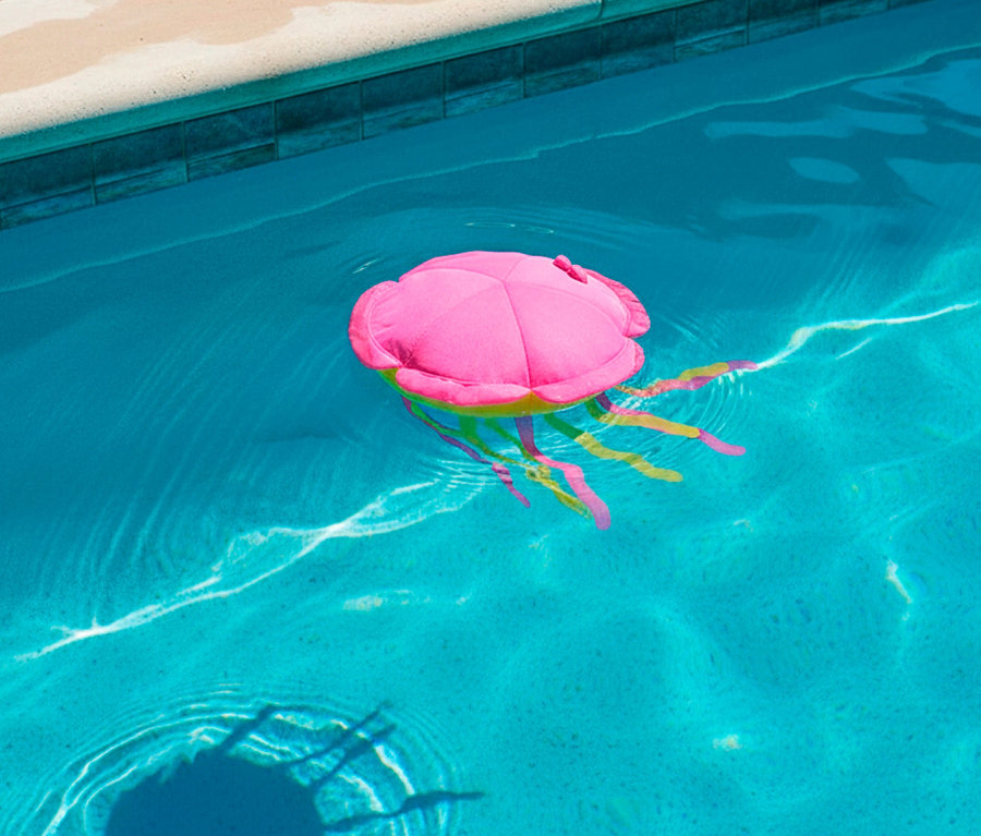 Eine pinke Quallen-Poolboje schwimmt im blau getönten Wasser.