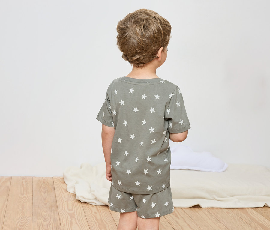 Ein Kind von hinten, trägt einen Schlafanzug mit Sternenmuster.