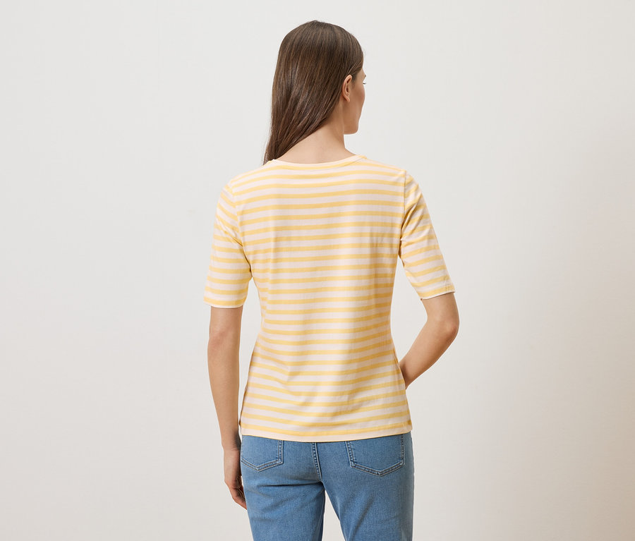 Rückansicht einer Frau mit langen braunen Haaren, die ein gelb-weiß gestreiftes T-Shirt und Jeans trägt.