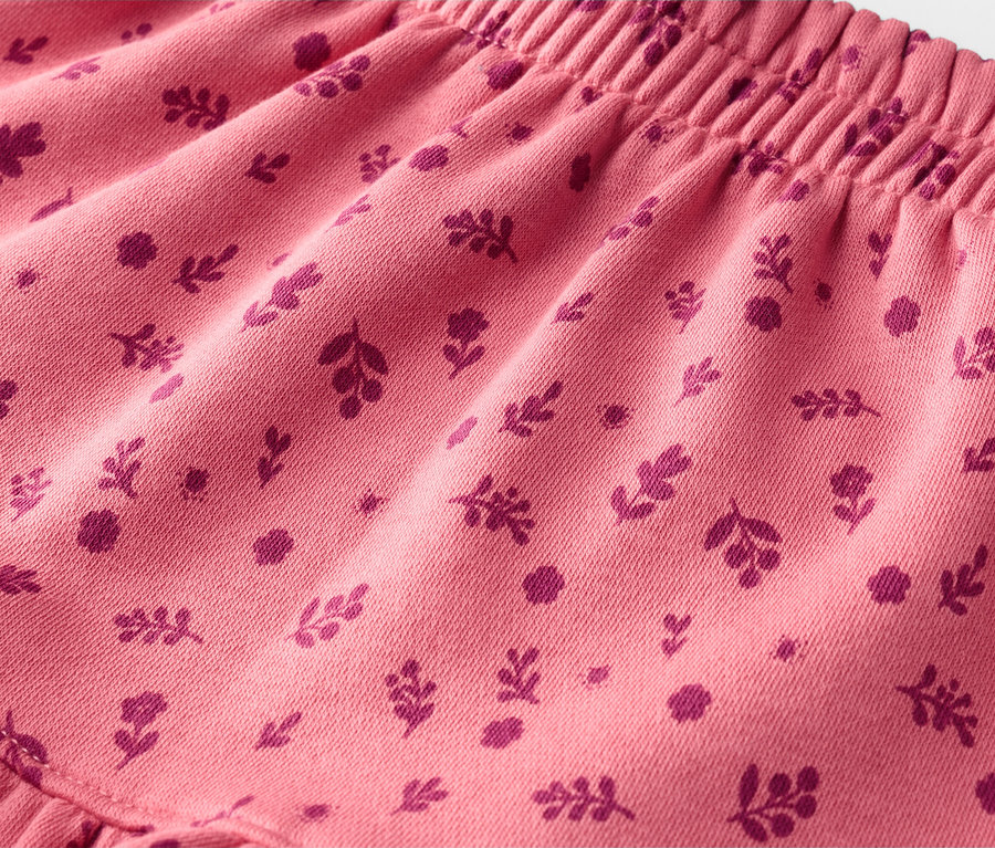 Nahaufnahme eines rosa Stoffes mit einem Muster aus kleinen, dunkelrosa Blumen und Blättern.