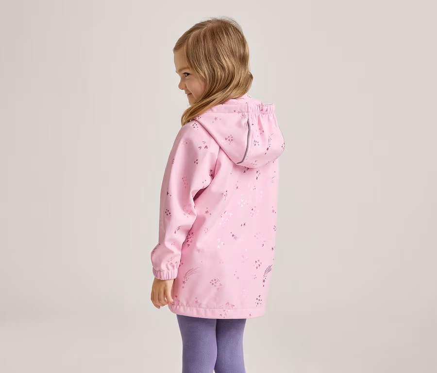 Mädchen von hinten in rosa, gemusterter Regenjacke mit Kapuze und lila Leggings.