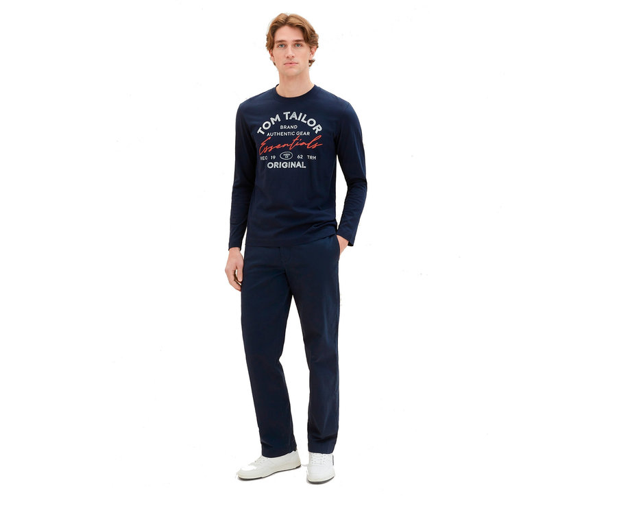 Mann in marineblauem Tom Tailor Longsleeve mit Logo, Sky Captain Blue und passender Hose, dazu weiße Schuhe.