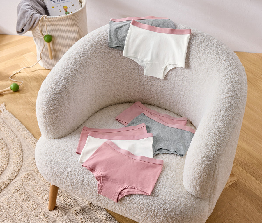 Mehrere altrosa Mädchen-Pantys (7er-Pack) liegen auf einem Sessel.