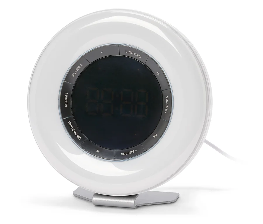 Runder, weißer Wecker mit digitaler Anzeige, der auf einem silbernen Ständer steht. Um das Display herum befinden sich Tasten für Beleuchtung, Alarm, Lautstärke und FM-Radio.