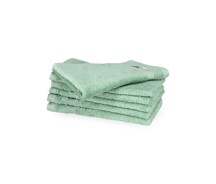Stapel von sechs salbeigrünen SCHÖNER WOHNEN-Kollektion Cuddly Gästehandtüchern auf weißem Hintergrund. Das oberste Handtuch liegt leicht schräg.
