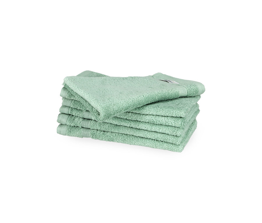 Stapel von sechs salbeigrünen SCHÖNER WOHNEN-Kollektion Cuddly Gästehandtüchern auf weißem Hintergrund. Das oberste Handtuch liegt leicht schräg.