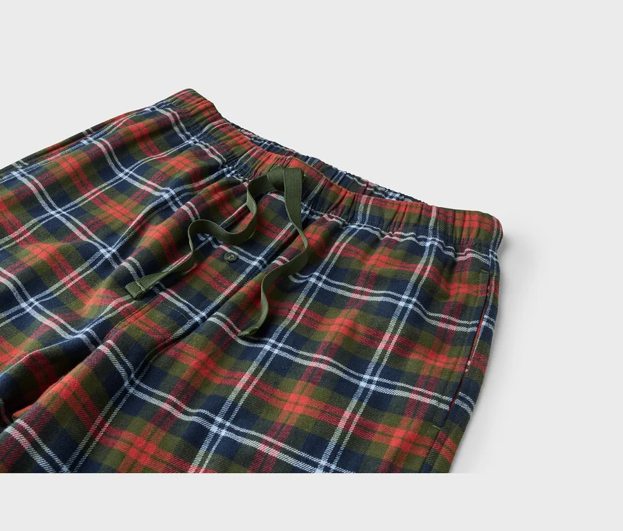 Nahaufnahme einer rot-grün-blau-weiß karierten Pyjamahose mit elastischem Bund, grünem Kordelzug und Knopfleiste.