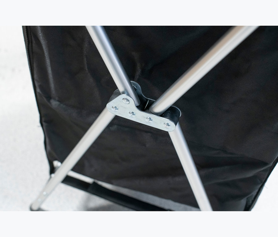Nahaufnahme des silbernen Metallgestells und des schwarzen Stoffes eines faltbaren Campingtisches mit Stauraum.