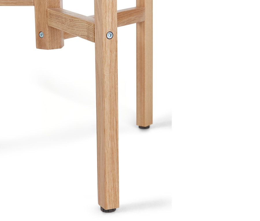 Detailaufnahme eines hellen Holzstuhl- oder Hockerbeins mit einem schwarzen Fuß.