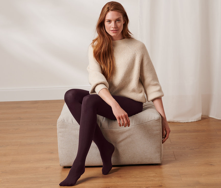 Frau sitzt auf einem Hocker und trägt eine Thermostrumpfhose.