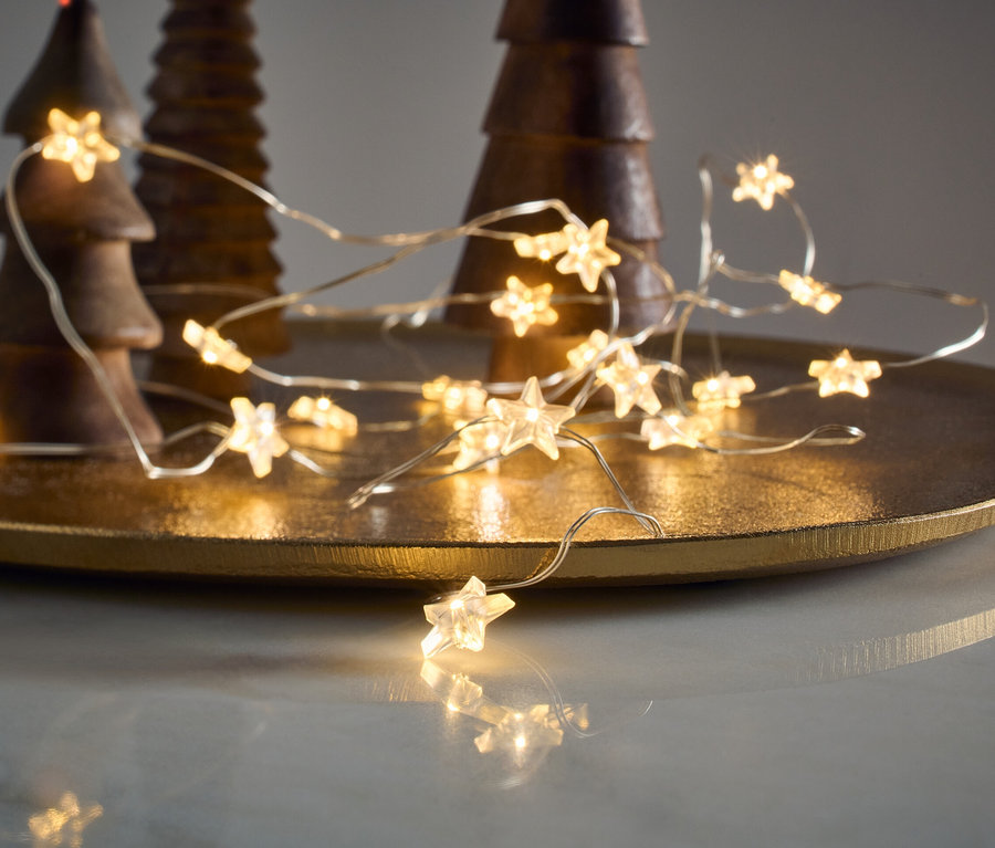 LED-Microlichterkette, Sterne, liegt auf einem goldenen Tablett neben hölzernen Zierbäumen.