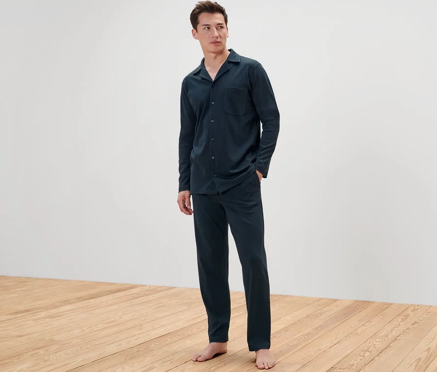 Mann steht barfuß und trägt einen Interlock-Pyjama.