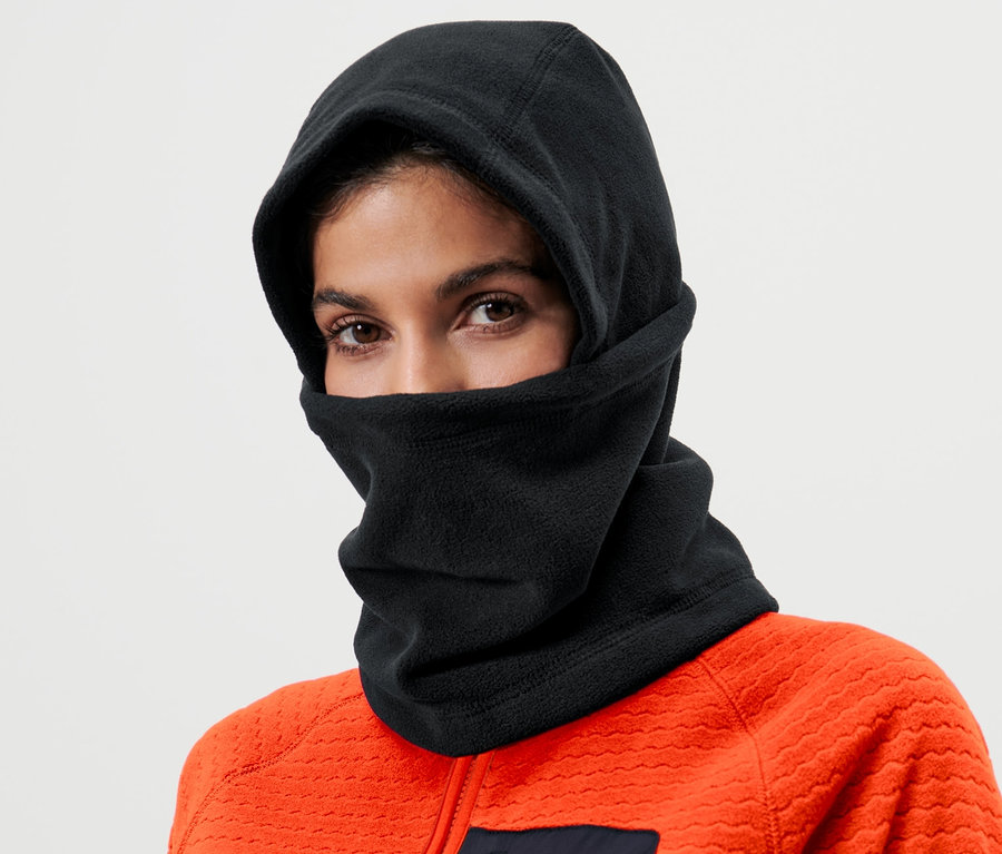 Frau trägt eine schwarze Microfleece-Sturmhaube und eine orangefarbene Jacke.