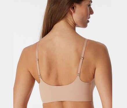 Rückansicht einer Frau mit braunen Haaren, die einen SCHIESSER Invisible Bustier mit Pads in Ahornfarbe trägt.