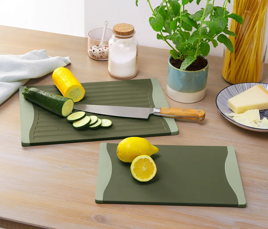 Zwei Schneidebretter mit geschnittener Zucchini, gelber Zucchini und Zitrone auf einem Holztisch.