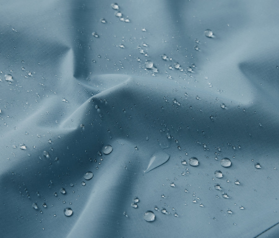 Detailaufnahme einer blauen Funktions-Outdoorjacke mit Wassertropfen.