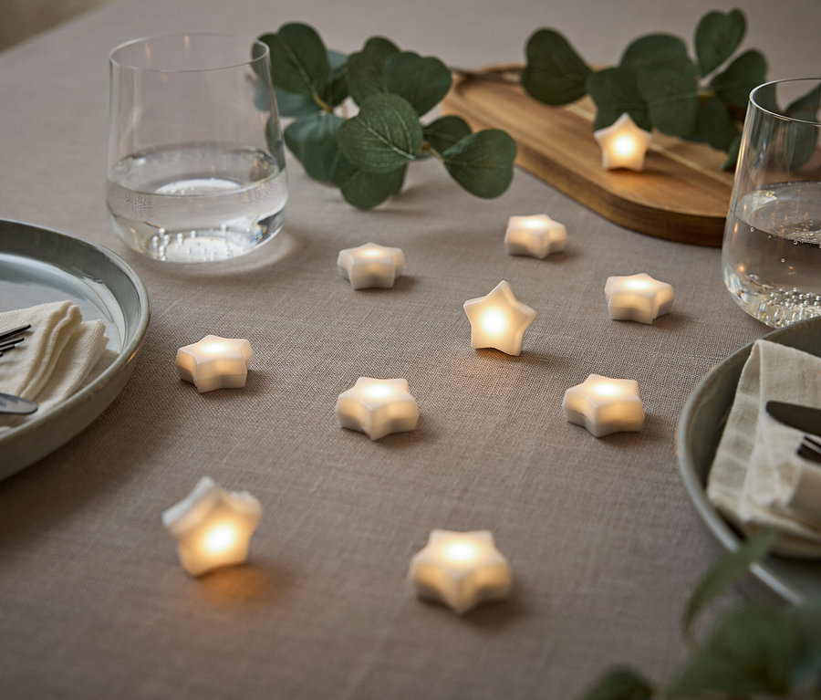 Gedeckter Tisch mit Sternen, Tellern, Wassergläsern und Eukalyptus.