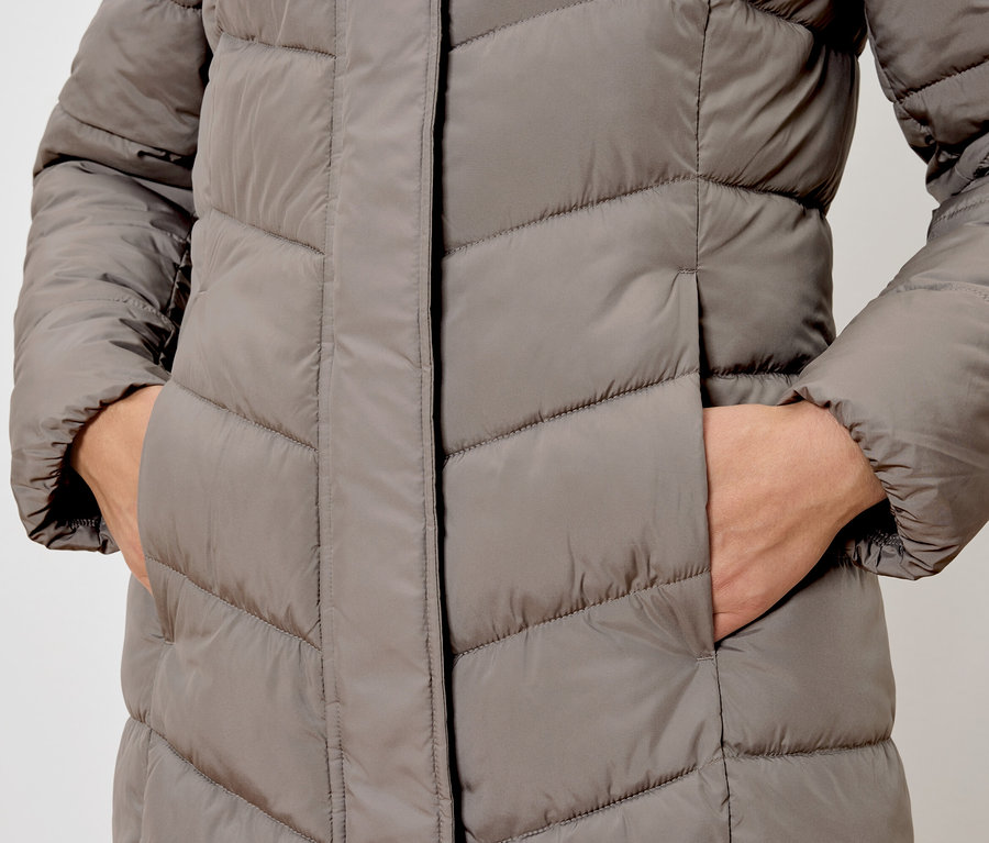 Detailaufnahme einer grauen Steppjacke mit einer Hand in der Tasche.