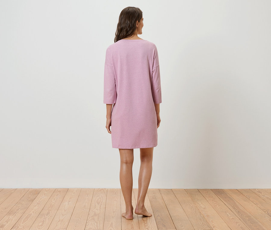 Frau steht mit dem Rücken zur Kamera und trägt ein rosa Kleid mit Dreiviertelärmeln.