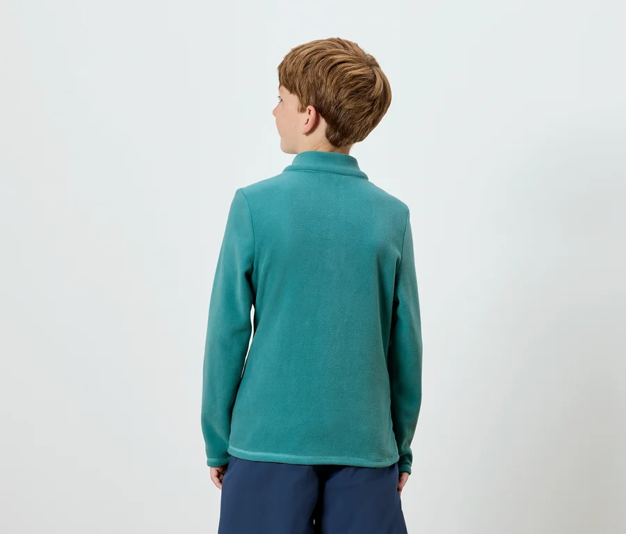 Von hinten ist eine Person mit kurzem braunem Haar zu sehen, die ein blaugrünes Langarm-Top und marineblaue Shorts trägt.