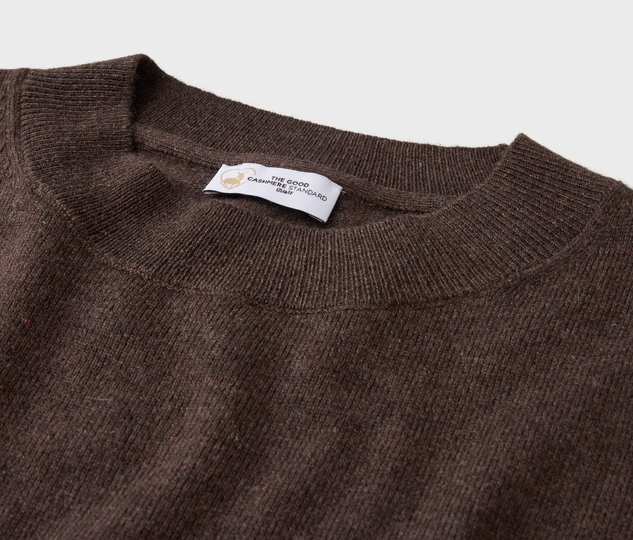 Detailaufnahme eines braunen Rundhals-Pullovers mit Etikett.