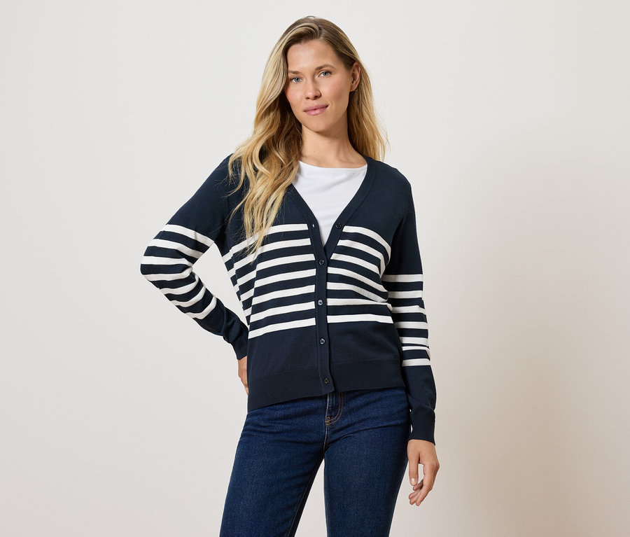 Frau posiert in marineblauer, gestreifter Strickjacke und Jeans.