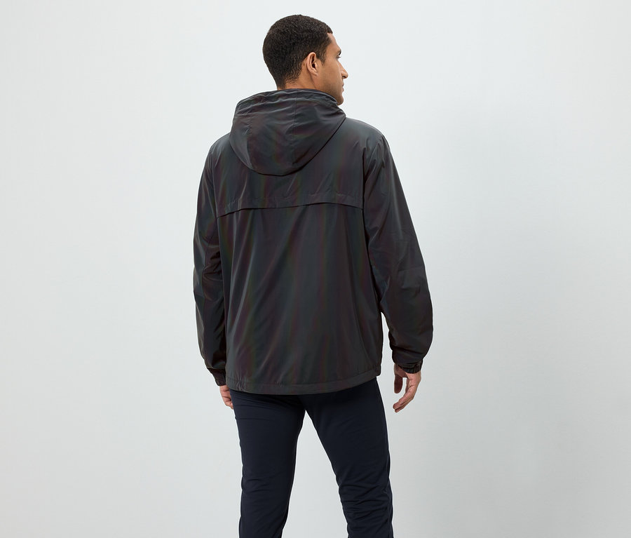 Mann von hinten, trägt eine schillernde Jacke mit Kapuze und dunkelblaue Hose.